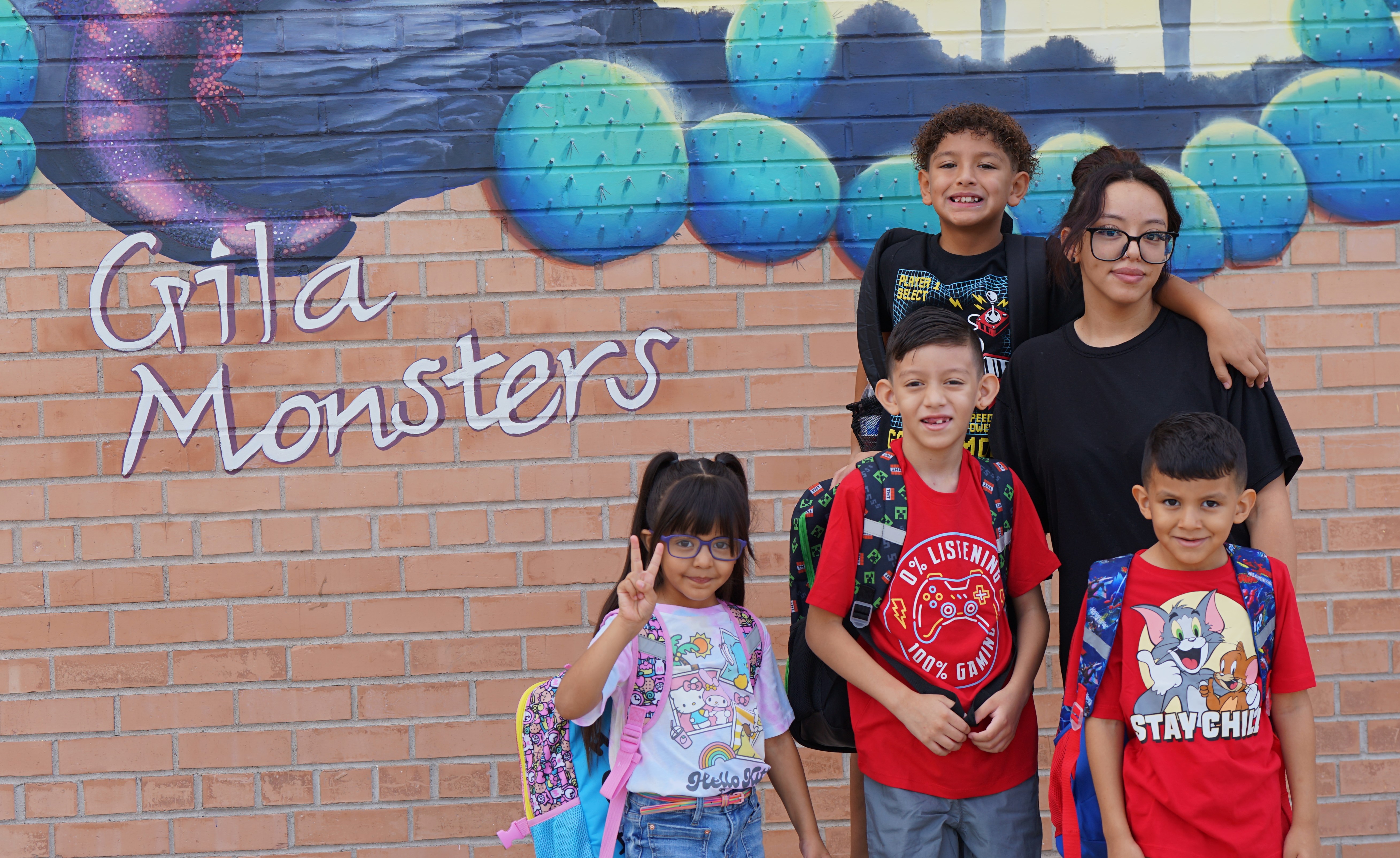 A mom and her four kids pose in front of the Henry Gila Monsters mural