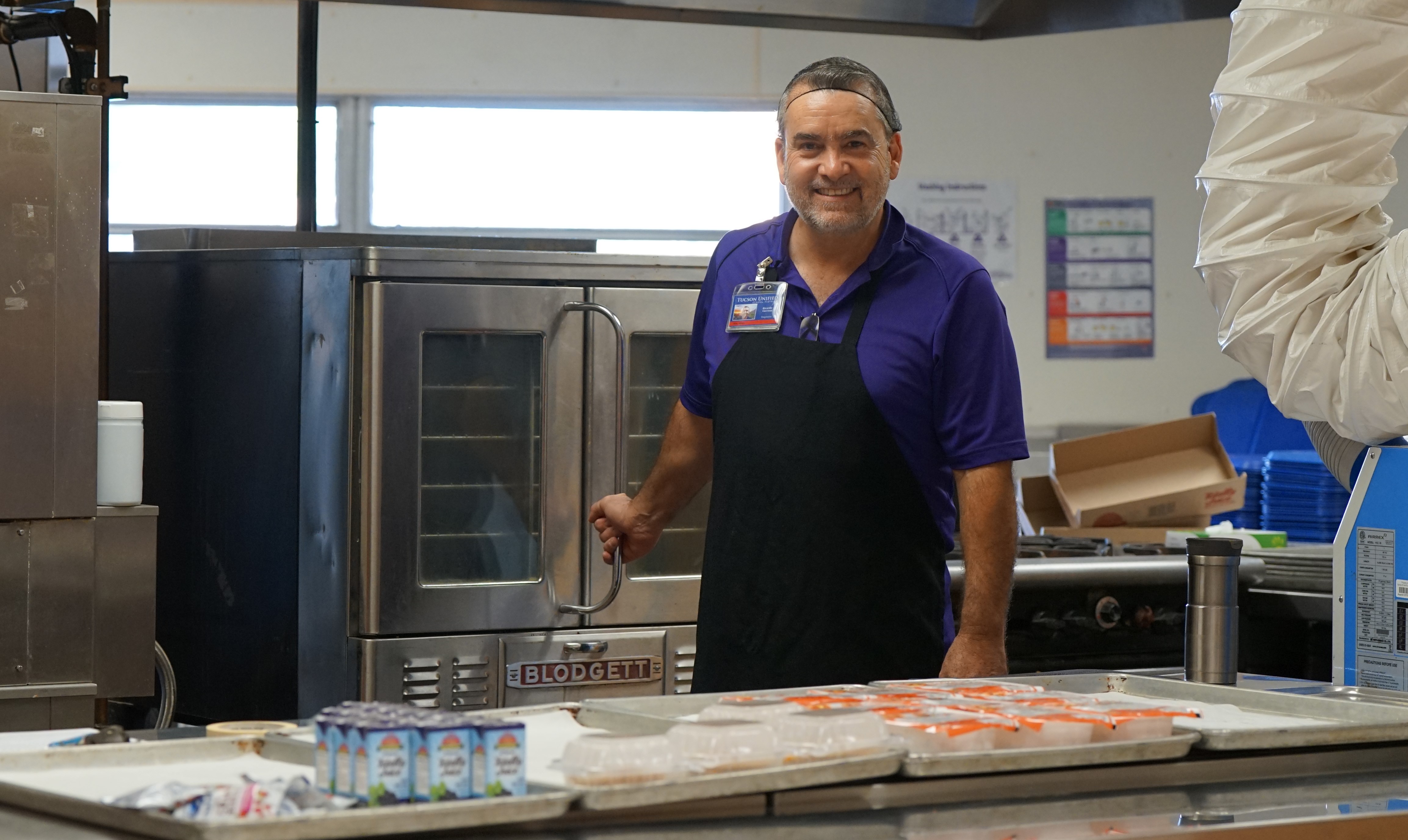 A cafeteria worker smiles as he prepares lunch for students