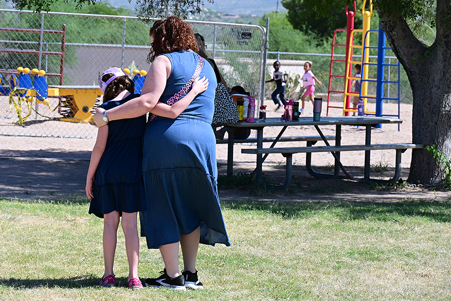 A girl and woman hug outside by the playground