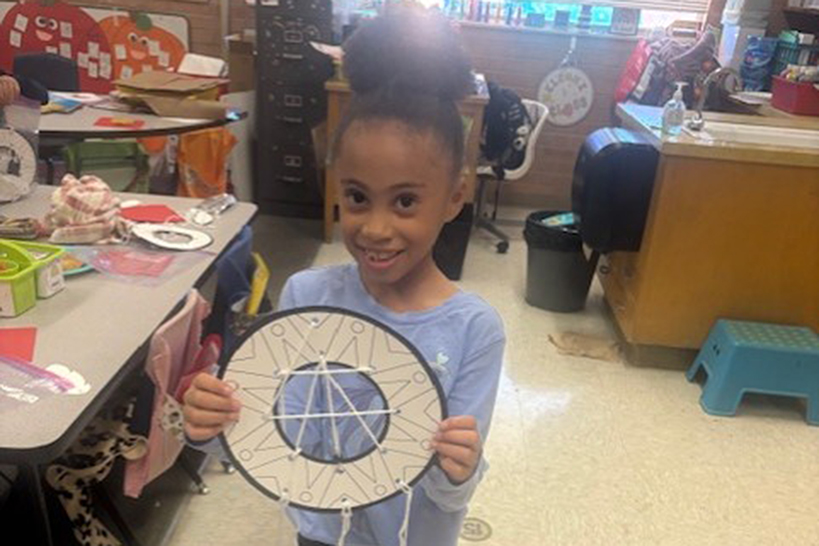 A little girl shows off the dreamcatcher she made
